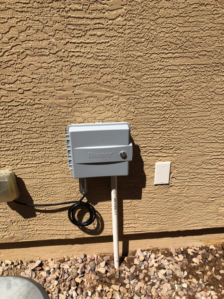 Hunter Hydrawise WiFi irrigation controller mounted on a textured wall, showcasing irrigation system management for efficient landscaping in Phoenix, AZ.