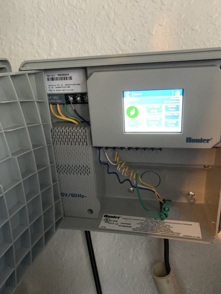Irrigation control box timer with digital display and wiring, used for managing sprinkler systems in Phoenix, AZ.
